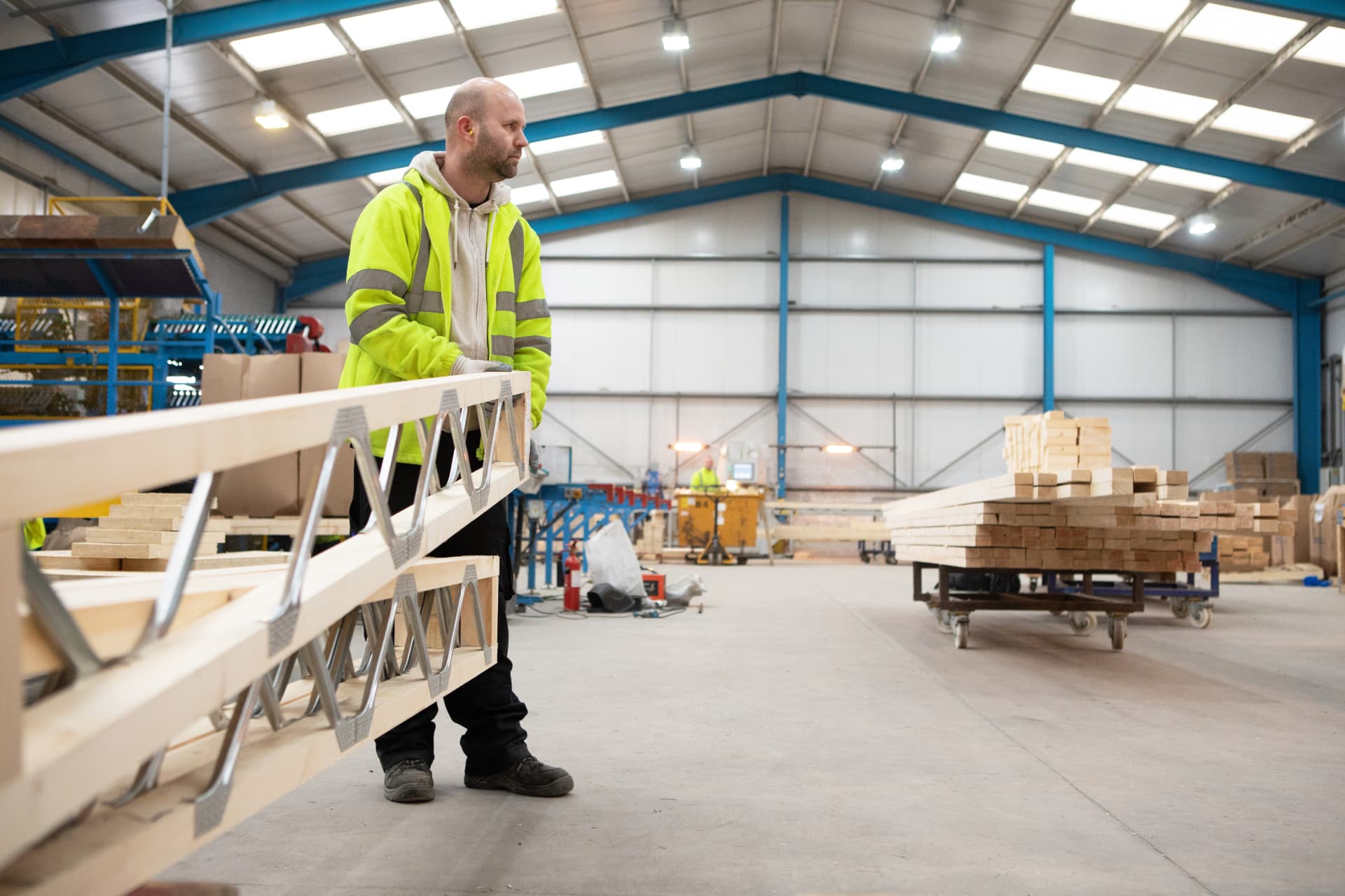DTE operative carrying a Posi-Joist across the production hall
