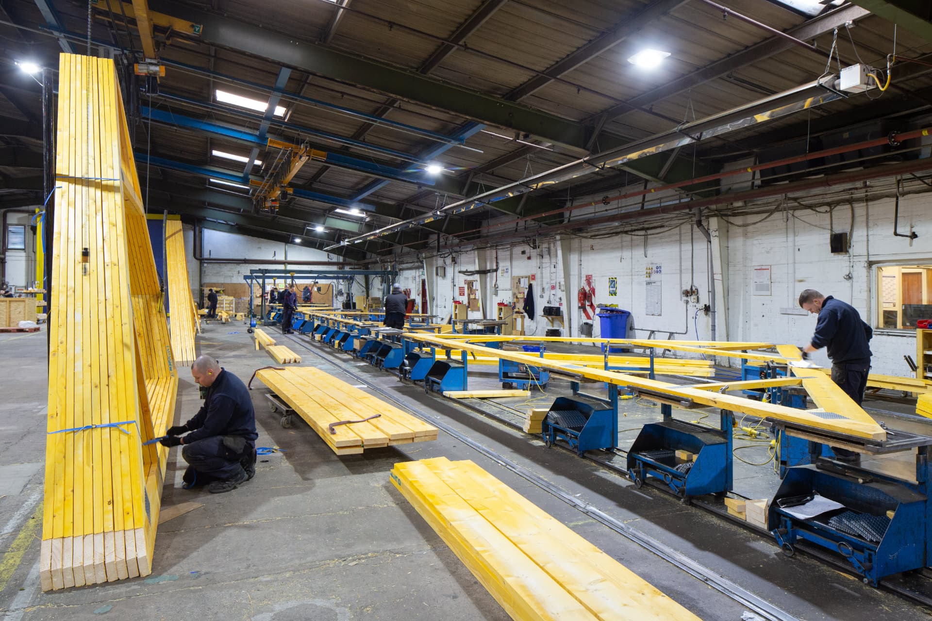 Long truss assembly line with joinery benches inside a DTE manufacturing hall